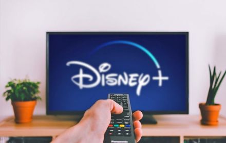 Hand en afstandsbediening met scherm Disney+