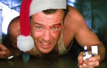 Bruce Willis in Die Hard met een kerstmuts op zijn hoofd gephotoshopt. 